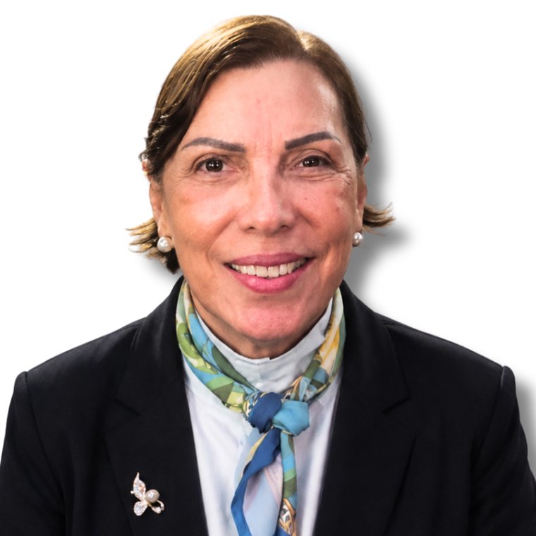 Retrato de Lucinha Garcia, sorrindo, de blazer escuro e lenço azul e verde